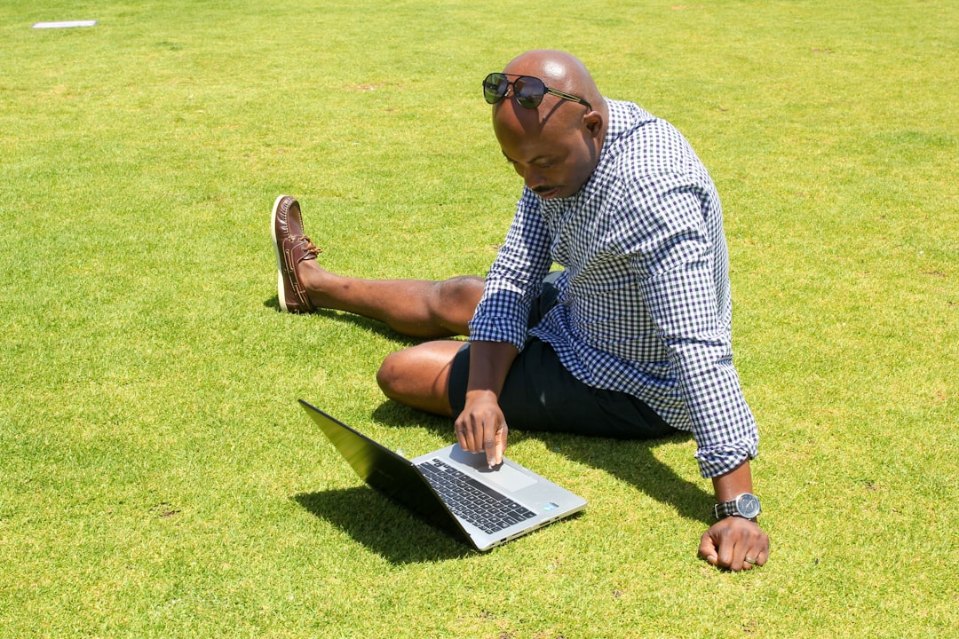 Black guy working on a laptop in a field